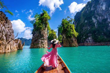 Güzel kız teknede oturan ve Khao Sok Milli Parkı Ratchaprapha Barajı dağlara bakıyor, Surat Thani Eyaleti, Tayland.