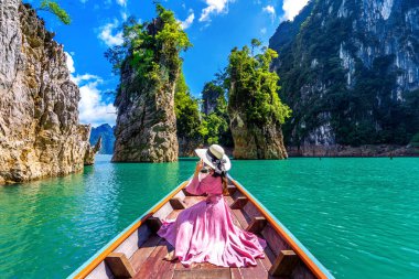 Güzel kız teknede oturan ve Khao Sok Milli Parkı Ratchaprapha Barajı dağlara bakıyor, Surat Thani Eyaleti, Tayland.