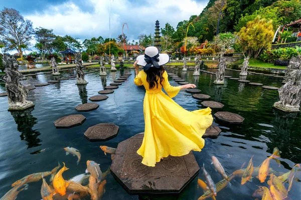 インドネシア、バリ島のティルタ・ガンガ・ウォーター・パレスでカラフルな魚と池に立つ女性. — ストック写真