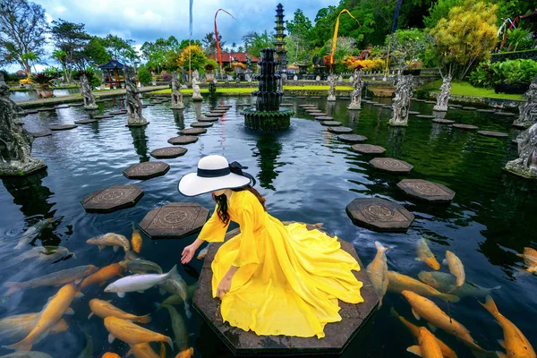 Perempuan yang makan ikan berwarna-warni di kolam di Istana Air Tirta Gangga di Bali, Indonesia . — Stok Foto