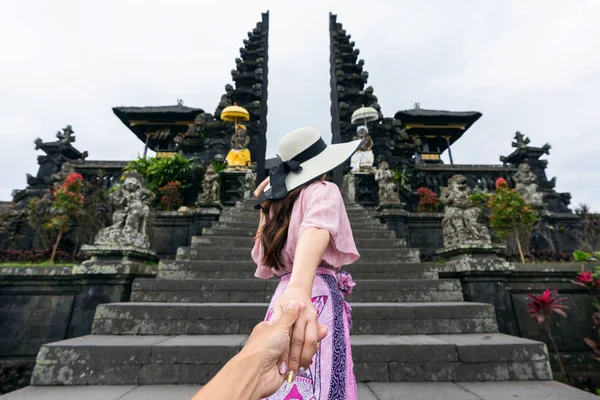 Mujeres turistas sosteniendo la mano del hombre y llevándolo al templo Besakih en Bali, Indonesia . —  Fotos de Stock