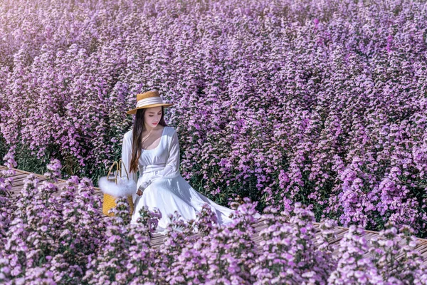 美しいです女の子で白いドレスでマーガレットの花のフィールドに座って — ストック写真