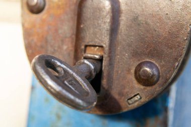 İçinde anahtar olan eski bir asma kilit.