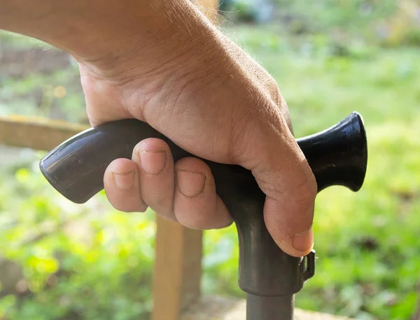 Bir adamın elinde siyah bir baston, yakın mesafeden bir fırça.