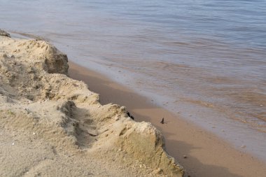 Nehir, suda küçük dalgalar, yavaş akıntı, sarı kum kıyısı..
