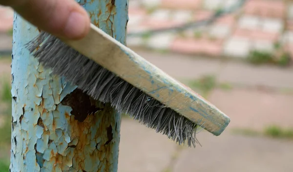 Demir bir fırçayla demir bir borudan eski boyayı çıkarıyorum..