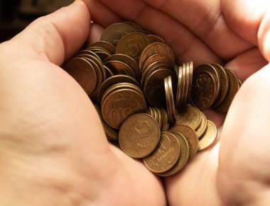 Bir insanın elinde bir sürü sarı para vardır..