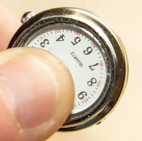 Elinde küçük gümüş bir saat, üzerinde 