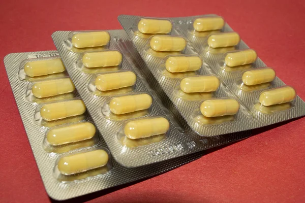 Kırmızı masada üç sarı hap tabağı..