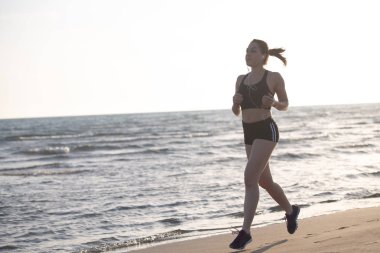 Sağlıklı genç kadın gündoğumu sahil yolu üzerinde çalışan müzik dinlemek yerleştirmek