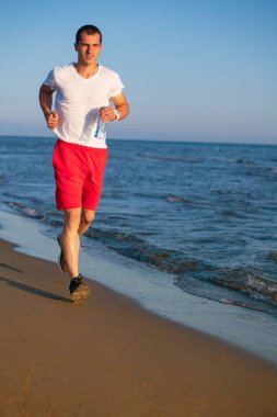 Mavi deniz ve gökyüzü karşı sahilde koşu su şişe tutan adam önden görünümü