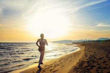 Uygun kadın holding şişe su sahil yolu üzerinde çalışan arka görünümü