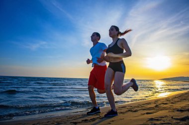 Adam ve tropikal deniz kenarında günbatımında çalışan kadın yan görünüm