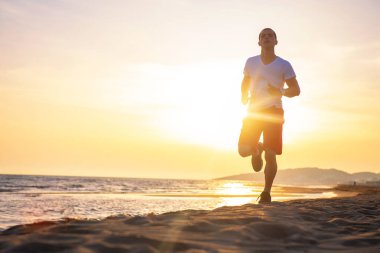 Sağlıklı bir insan günbatımı gökyüzü karşı sahilde koşu önden görünümü