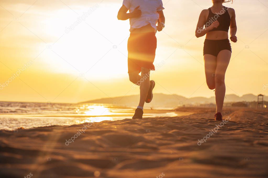 Ground view of young couple running together by tropical beach at sunset