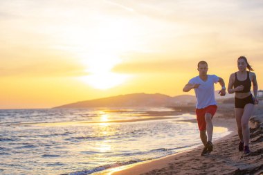 Günbatımında tropik plajda koşan erkek ve kadınlar