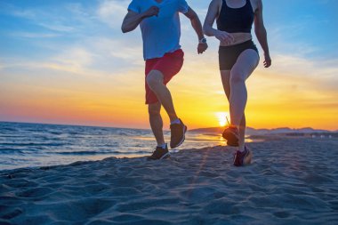 Günbatımında tropik plajda koşan erkek ve kadınlar