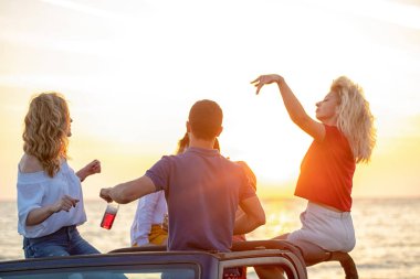 Grup günbatımı sırasında Plajı'nda Cabrio araba içinde eğleniyor içecekler genç insan