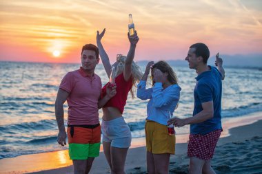 İki çiftler kumsalda günbatımı sırasında dinlenme