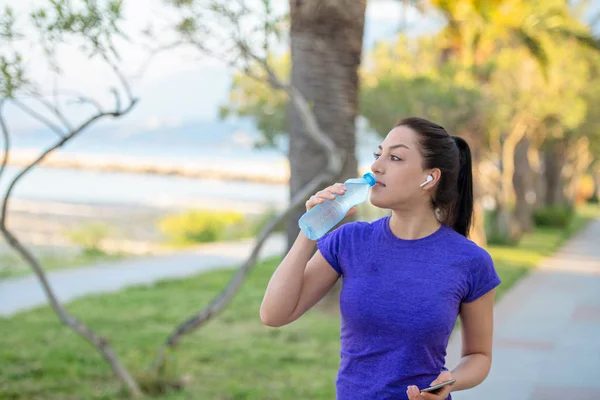 若い女性が朝のジョギング中に水を飲む — ストック写真