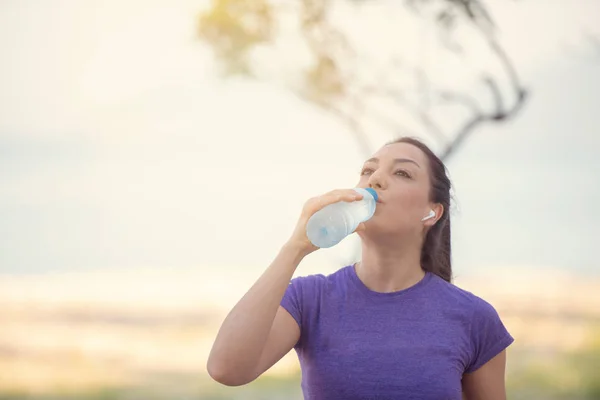 若い女性が朝のジョギング中に水を飲む — ストック写真