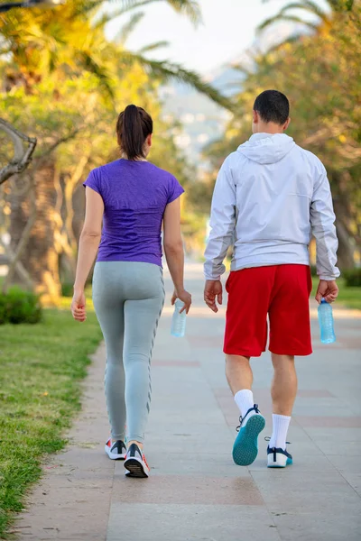 若いスポーティな男と女 ジョギング後の路地を歩いてスポーツウェアの背面図 — ストック写真