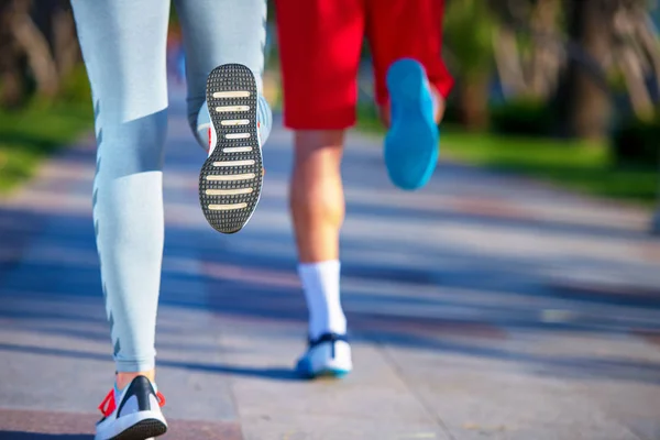 legs of man and woman  in sportswear jogging at beach, back view