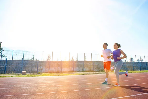 年轻运动的夫妇慢跑在体育场跑的轨道 — 图库照片