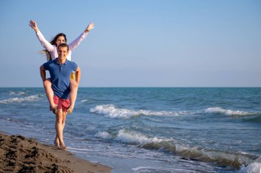  Sahilde sırtında kadın taşıyan bir adam.