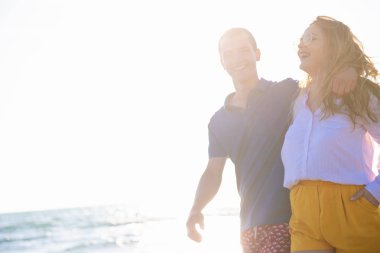 kaygısız erkek ve kadın denizde kıyıya günbatımında yürüyüş