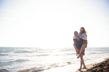  Sahilde sırtında kadın taşıyan bir adam.