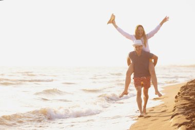  Sahilde sırtında kadın taşıyan bir adam.