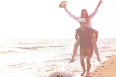  Sahilde sırtında kadın taşıyan bir adam.