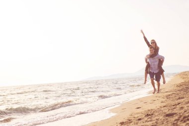  Sahilde sırtında kadın taşıyan bir adam.