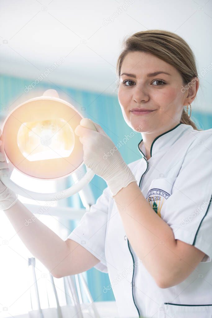 happy young female dentist with tools over medical office background, dentistry and healthcare concept