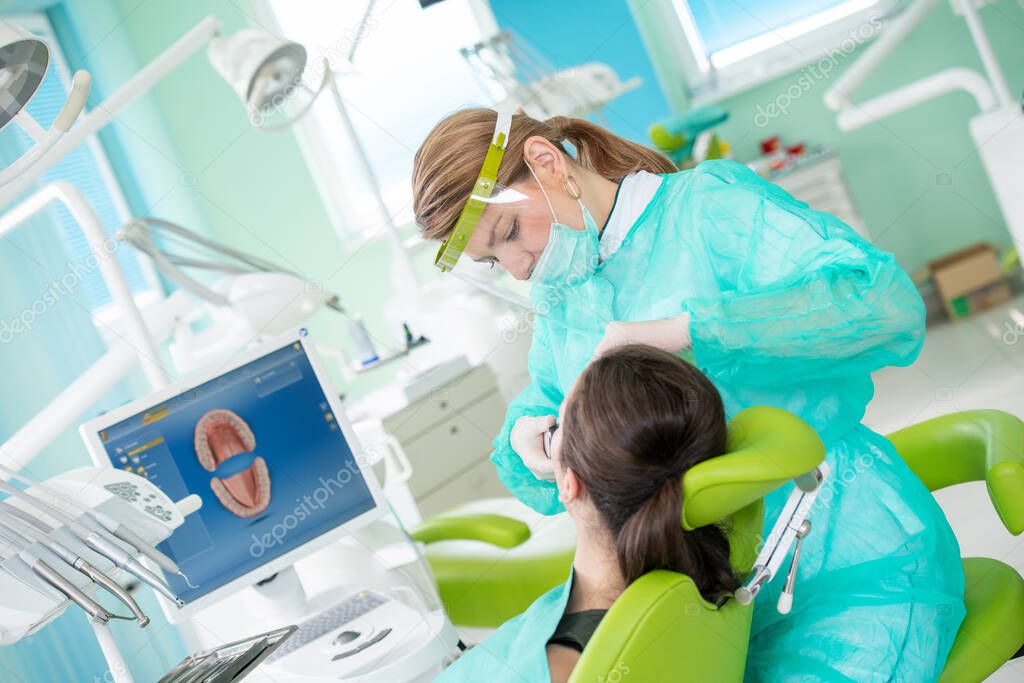 Female dentist and young woman patient in dentist office  