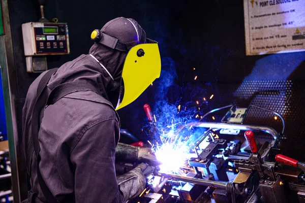 Man Welding on Assembly Line in Automotive Factory .