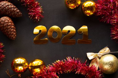 Yeni Yıl şekerleri ve siyah arkaplanda 2021 yazısıyla süslenmiş süslemeler..