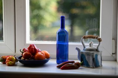 Pencere kenarındaki cam şişede taze sebzeler.