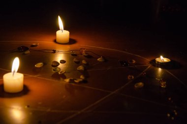 Pentagram yere boyanır, mumlar yakılır, boncuklar yerde yatar, kabuklar dağılır. Okült ve esrarengiz sembollerle büyü kavramı.
