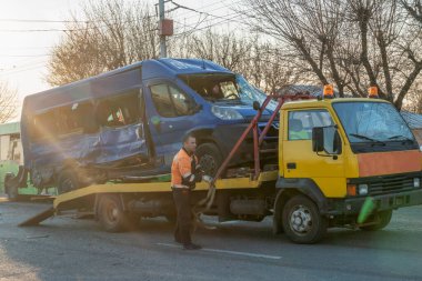 Mogilev, Belarus - 16 Nisan 2019: Güneşli bir günde kırık mavi bir minibüsü sokağın ortasında sarı bir çekiciye yüklemek