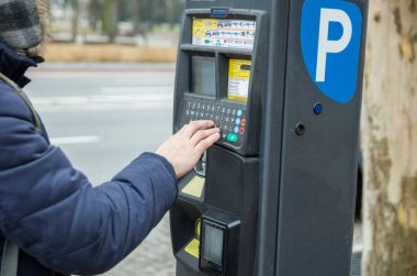 Adam arabayı park etmek için para ödüyor.