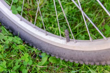 Bisiklet tekerleğinin detayları. Çimlere yakın çekimde çarkın ucunda meme ucu.