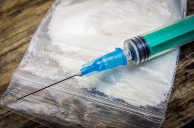 Bir torba uyuşturucu, ahşap arka planda yakın plan şırınga.