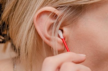 Bir kadın pamuklu çubukla kulaklarını temizliyor..