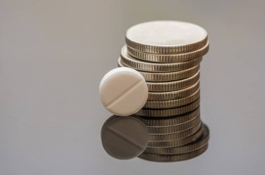 Bozuk para yığınıyla ilgili beyaz hap arka planda yansıtılır