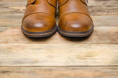 Erkeklerin kahverengi ayakkabılarının yuvarlak burnu ahşap arka planda yakın planda, uzayın bir kopyasıyla birlikte.