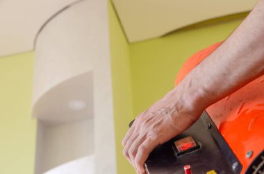 İşçi bir ısı tabancası tutuyor ve tavana doğrultuyor. Gerilme tavanı kurulumu. Boşluğu kopyala