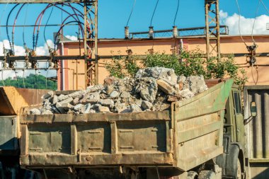 Büyük bir kamyon inşaat alanında taş taşıyor.