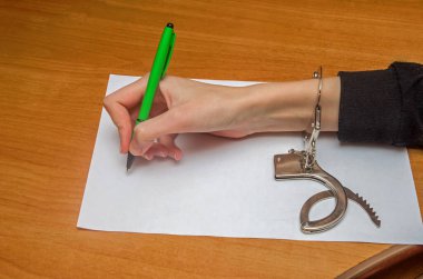 Kadın elleri kelepçeli, sabıka kaydını doldurmuş, itiraf etmiş. Tutuklama, kefalet, suç, hapis.